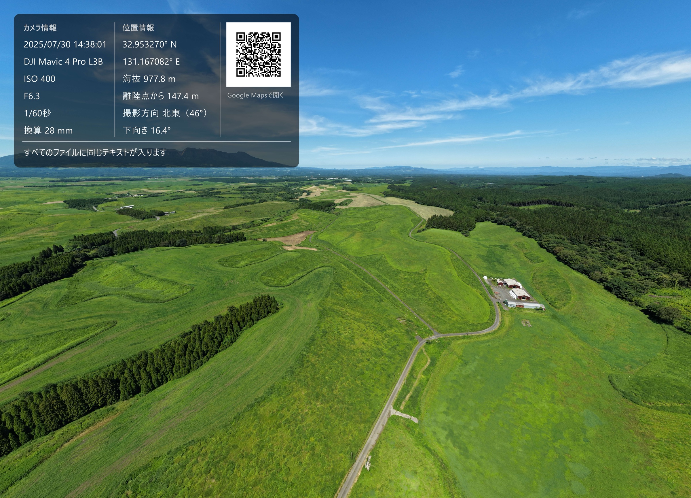 阿蘇の草原を空撮した写真。左上に撮影情報と地図の2次元コードが載っている